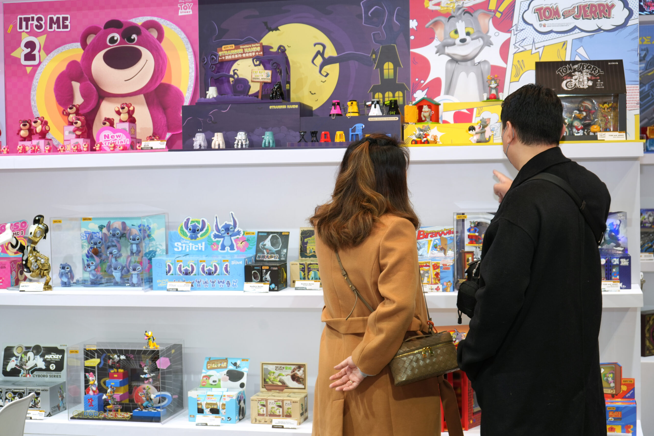 Toys Fair visitors looking at some cartoon giftboxes.